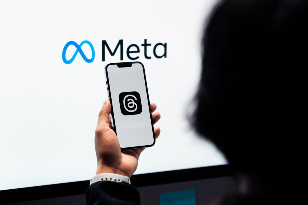 Main tenant un téléphone devant le logo Meta
