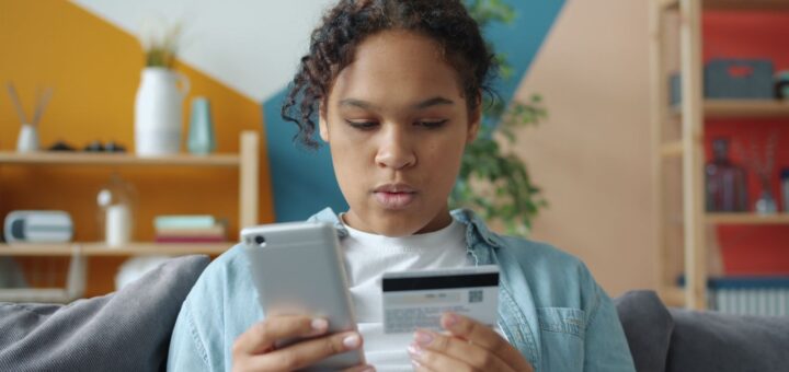 Jeune femme qui achète en ligne avec son téléphone et sa carte bancaire